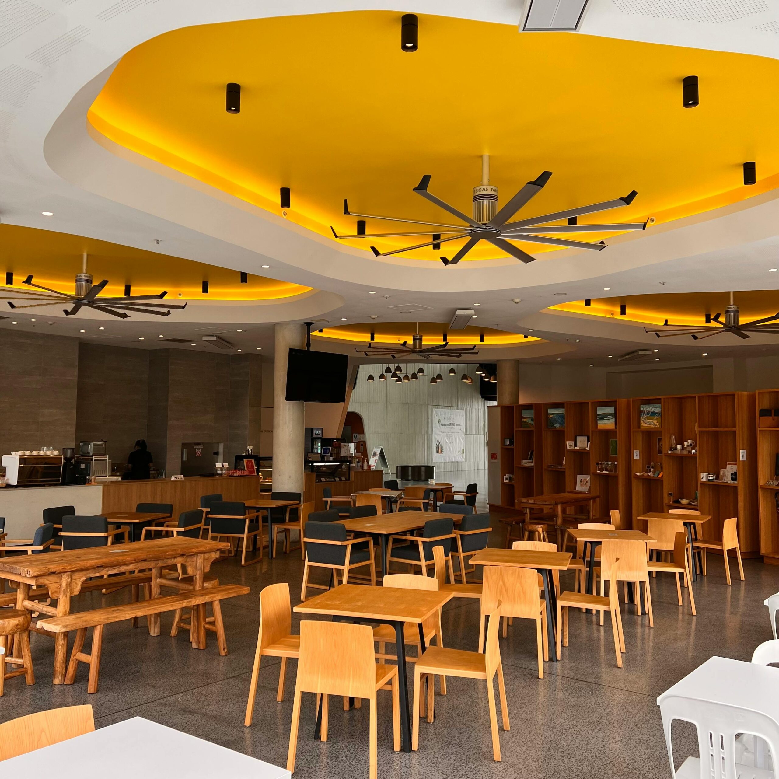 Stylish restaurant interior featuring a striking yellow ceiling design with modern furniture.