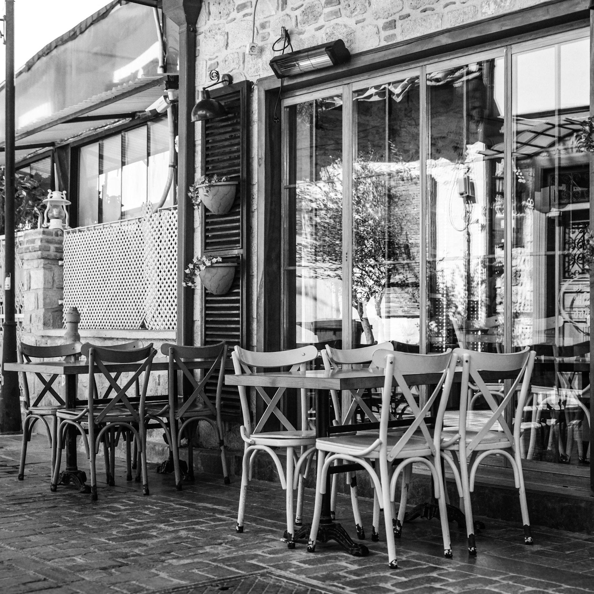 Empty outdoor cafe with vintage chairs and tables in black and white.